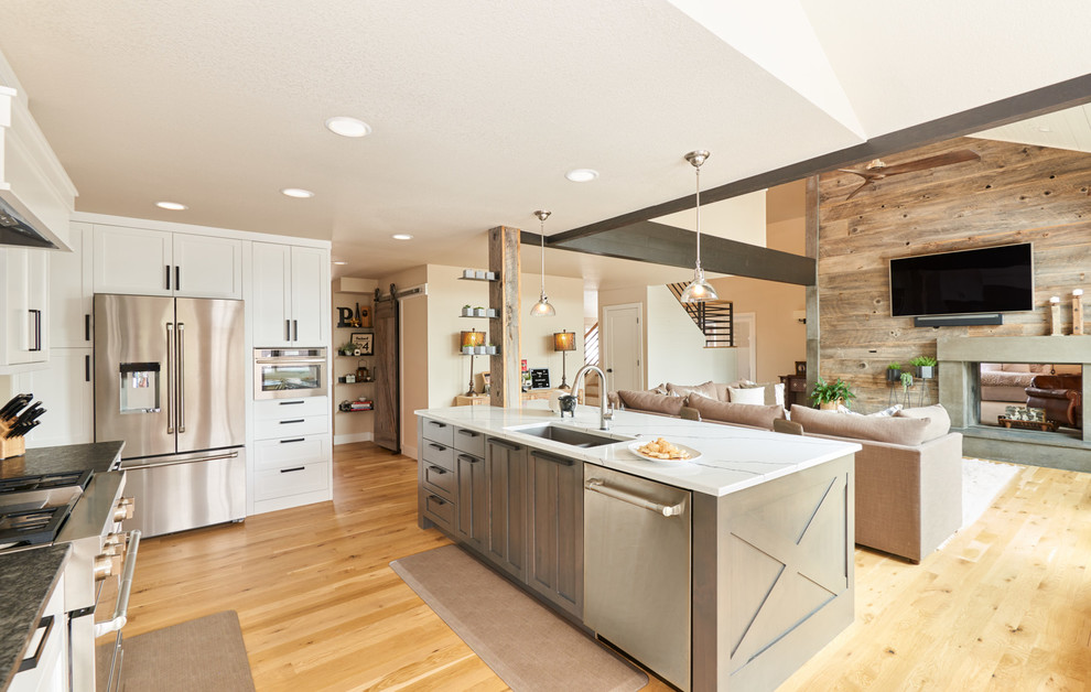 Example of a large trendy l-shaped light wood floor and brown floor open concept kitchen design in Denver with an undermount sink, shaker cabinets, brown cabinets, quartz countertops, black backsplash, ceramic backsplash, stainless steel appliances, an island and white countertops