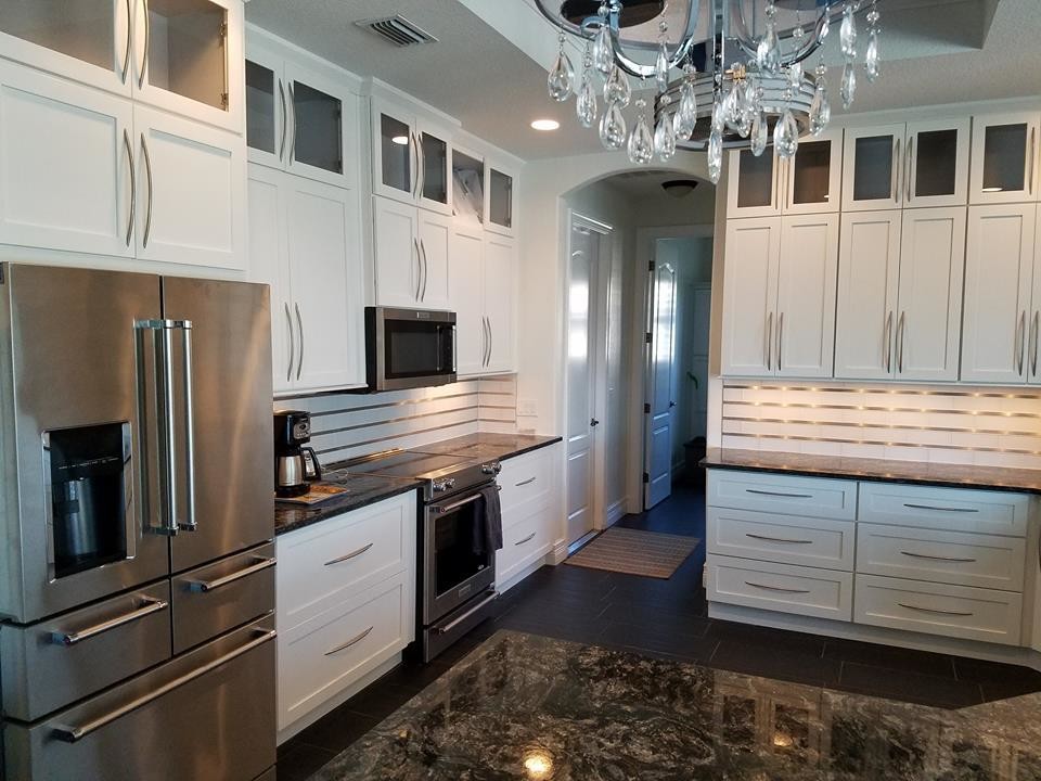 Medium sized traditional u-shaped open plan kitchen in Miami with a submerged sink, shaker cabinets, stainless steel cabinets, granite worktops, stainless steel appliances, dark hardwood flooring, an island and brown floors.
