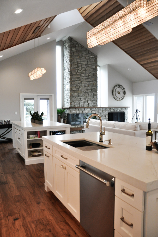 Example of a large trendy medium tone wood floor, brown floor and wood ceiling eat-in kitchen design in Other with an undermount sink, shaker cabinets, white cabinets, quartz countertops, white backsplash, quartz backsplash, paneled appliances, two islands and white countertops