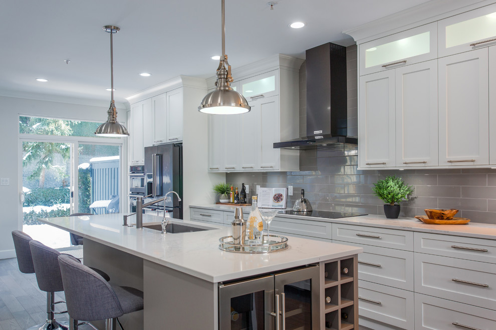 Zweizeilige Moderne Küche mit Schrankfronten im Shaker-Stil, weißen Schränken, Quarzwerkstein-Arbeitsplatte, Küchenrückwand in Grau, dunklem Holzboden und Kücheninsel in Vancouver