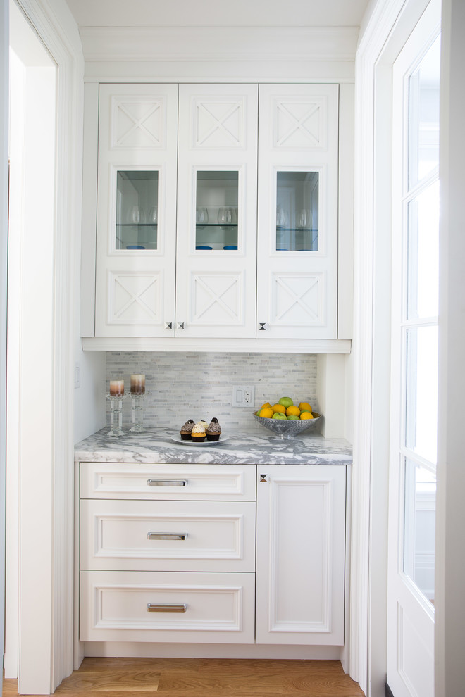 Ejemplo de cocina tradicional con puertas de armario blancas, encimera de mármol, salpicadero blanco, electrodomésticos con paneles y suelo de madera clara