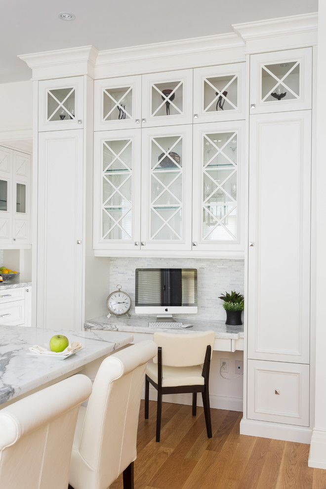 Klassische Küche mit weißen Schränken, Marmor-Arbeitsplatte, Küchenrückwand in Weiß, Rückwand aus Stäbchenfliesen, Elektrogeräten mit Frontblende, braunem Holzboden und Glasfronten in Toronto