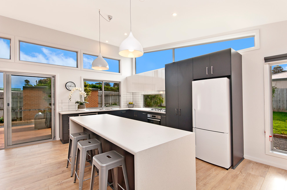 Inspiration for a medium sized contemporary l-shaped kitchen/diner in Geelong with a double-bowl sink, flat-panel cabinets, blue cabinets, laminate countertops, multi-coloured splashback, metro tiled splashback, stainless steel appliances, bamboo flooring and an island.