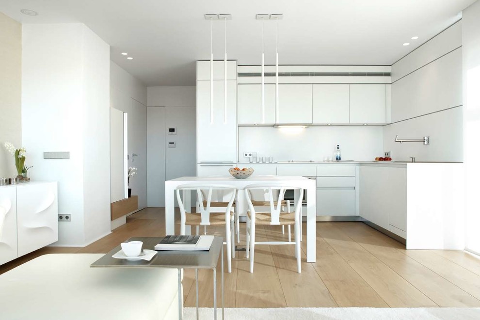 Inspiration for a mid-sized contemporary l-shaped light wood floor open concept kitchen remodel in Los Angeles with flat-panel cabinets, white cabinets, white backsplash, no island and stainless steel appliances