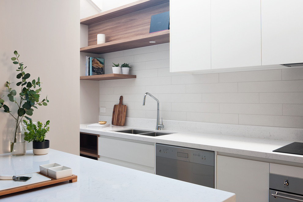 Inspiration for a large contemporary galley kitchen/diner in Melbourne with a built-in sink, beaded cabinets, white cabinets, white splashback, metro tiled splashback, stainless steel appliances and an island.