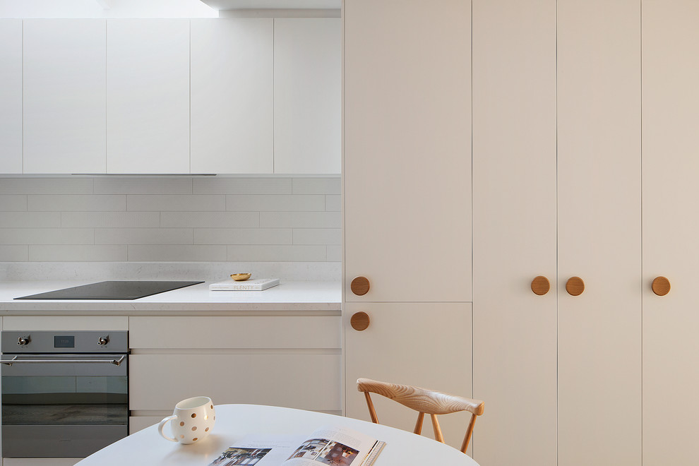 Large contemporary galley kitchen/diner in Melbourne with a built-in sink, beaded cabinets, white cabinets, white splashback, metro tiled splashback, stainless steel appliances and an island.