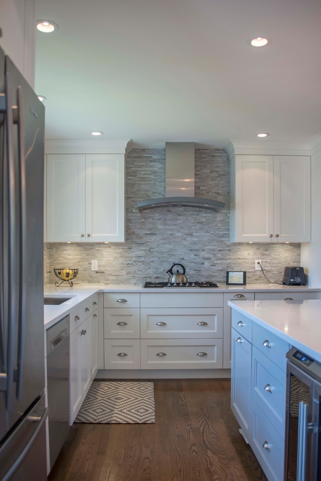 Medium sized traditional l-shaped open plan kitchen in Vancouver with a submerged sink, shaker cabinets, white cabinets, engineered stone countertops, multi-coloured splashback, stone tiled splashback, stainless steel appliances, medium hardwood flooring, an island, brown floors and white worktops.
