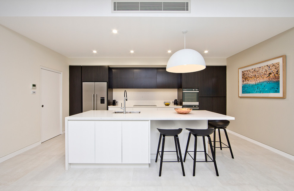 Moderne Küche mit Unterbauwaschbecken, flächenbündigen Schrankfronten, dunklen Holzschränken, Küchenrückwand in Weiß, Küchengeräten aus Edelstahl und Kücheninsel in Sydney