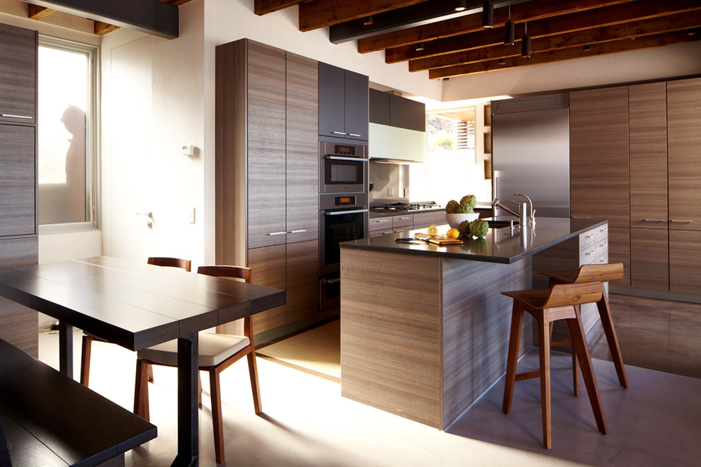Mid-sized minimalist l-shaped concrete floor eat-in kitchen photo in New York with stainless steel appliances, flat-panel cabinets, dark wood cabinets, quartz countertops, an undermount sink and an island
