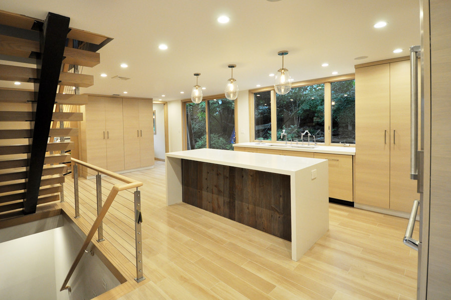Inredning av ett modernt mellanstort kök, med en undermonterad diskho, släta luckor, skåp i mellenmörkt trä, bänkskiva i kvartsit, grönt stänkskydd, stänkskydd i glaskakel, rostfria vitvaror, klinkergolv i porslin, en köksö och beiget golv