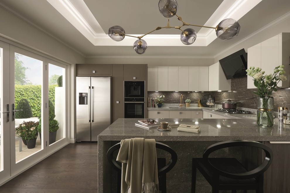 Mid-sized transitional u-shaped dark wood floor and brown floor open concept kitchen photo in Dublin with a double-bowl sink, flat-panel cabinets, beige cabinets, concrete countertops, multicolored backsplash, limestone backsplash, black appliances and a peninsula