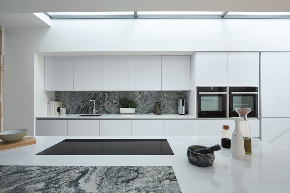 Inspiration for a medium sized contemporary galley kitchen/diner in Dublin with an integrated sink, flat-panel cabinets, white cabinets, quartz worktops, blue splashback, marble splashback, integrated appliances, light hardwood flooring, an island and brown floors.