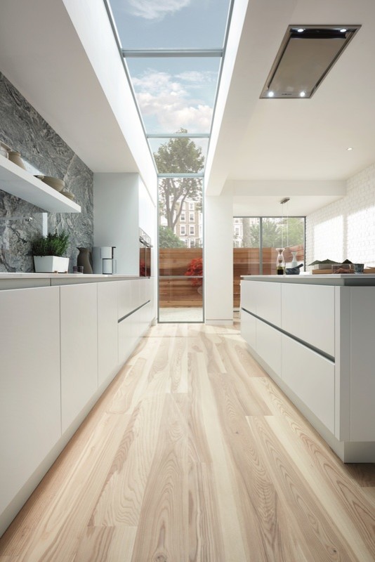 Bild på ett mellanstort funkis kök, med en integrerad diskho, släta luckor, vita skåp, bänkskiva i kvartsit, blått stänkskydd, stänkskydd i marmor, integrerade vitvaror, ljust trägolv, en köksö och brunt golv