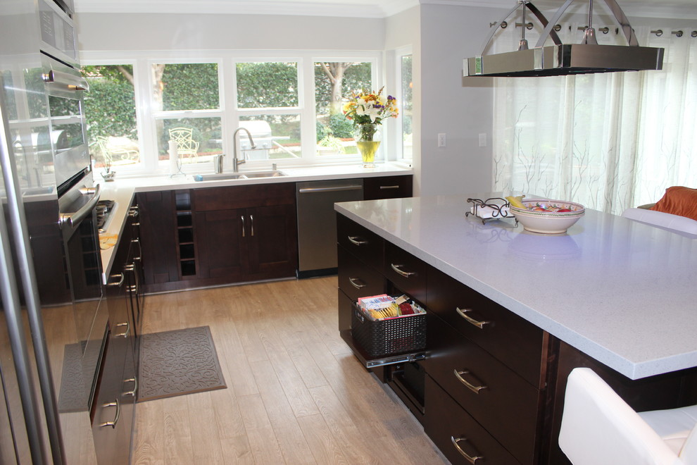 Example of a mid-sized minimalist l-shaped painted wood floor eat-in kitchen design in Los Angeles with a double-bowl sink, shaker cabinets, dark wood cabinets, quartz countertops, multicolored backsplash, glass sheet backsplash, stainless steel appliances and an island