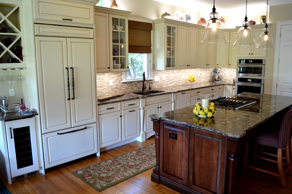 Bild på ett mellanstort vintage kök, med en undermonterad diskho, luckor med upphöjd panel, granitbänkskiva, beige stänkskydd, stänkskydd i stenkakel, integrerade vitvaror, ljust trägolv och en köksö