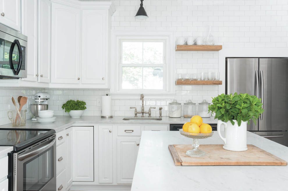 Bild på ett mellanstort vintage kök, med en nedsänkt diskho, vita skåp, marmorbänkskiva, vitt stänkskydd, stänkskydd i tunnelbanekakel, rostfria vitvaror, en köksö, mellanmörkt trägolv och brunt golv