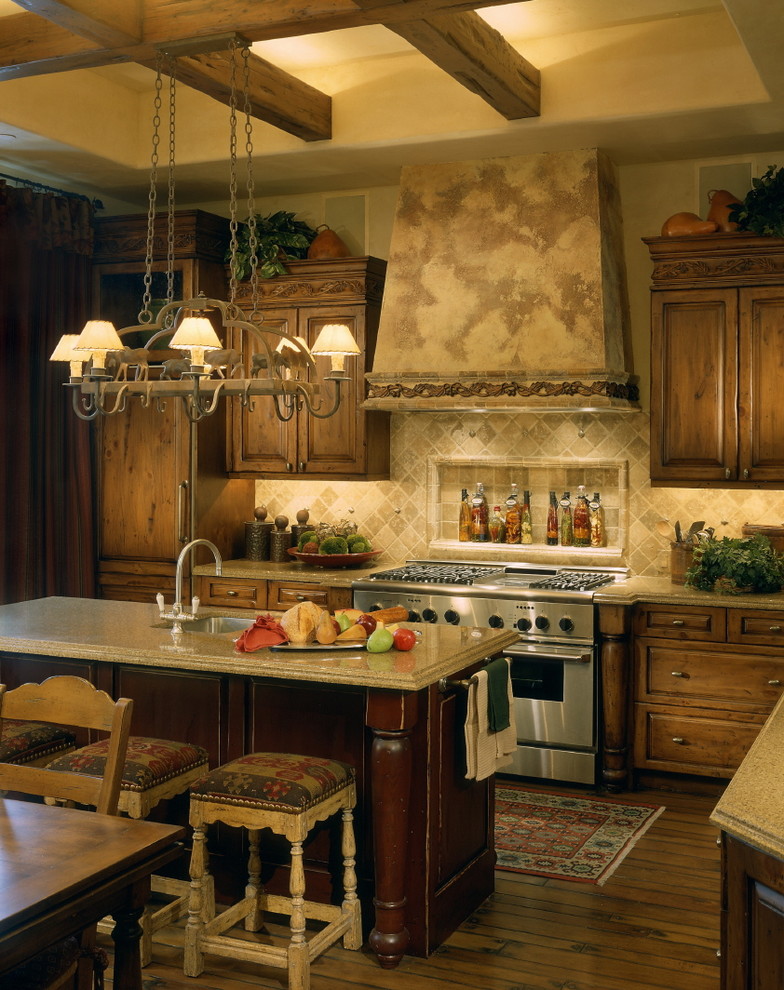 Photo of a medium sized rustic l-shaped kitchen/diner in Denver with a submerged sink, raised-panel cabinets, dark wood cabinets, granite worktops, beige splashback, stone tiled splashback, stainless steel appliances, dark hardwood flooring and an island.