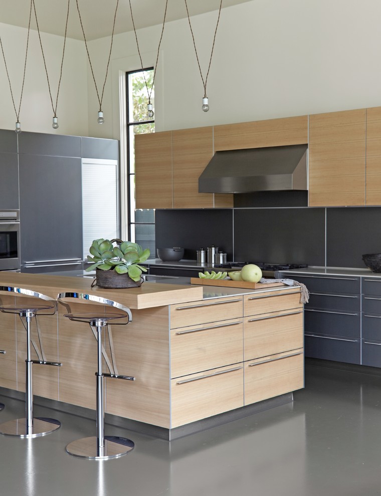 Inspiration for a large contemporary u-shaped concrete floor and gray floor eat-in kitchen remodel in New Orleans with flat-panel cabinets, light wood cabinets, stainless steel countertops, stainless steel appliances, an island and black backsplash