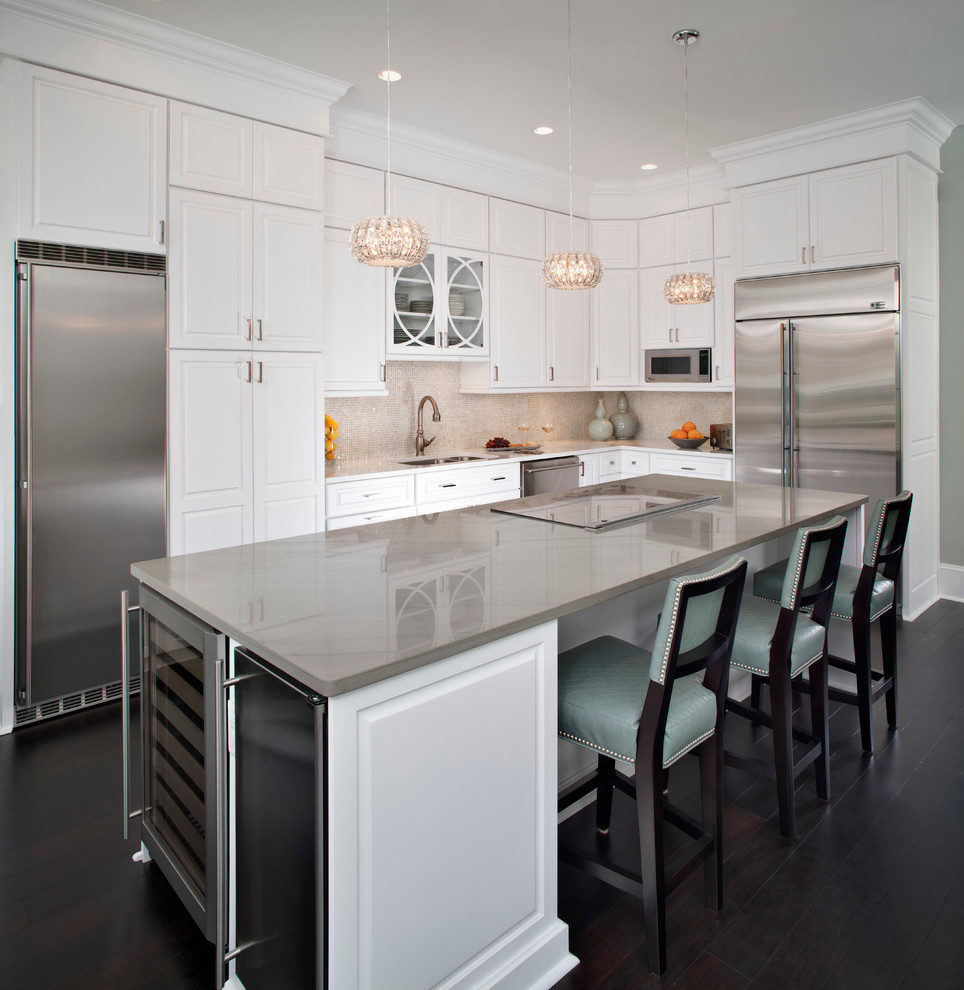 Traditional l-shaped kitchen/diner in DC Metro with raised-panel cabinets, white cabinets, beige splashback, stainless steel appliances and dark hardwood flooring.