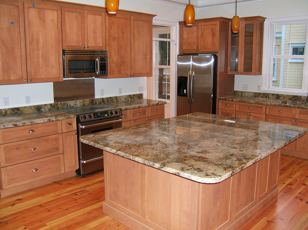 Example of a medium tone wood floor kitchen design in Charleston with a drop-in sink, recessed-panel cabinets, medium tone wood cabinets, granite countertops, stainless steel appliances and an island