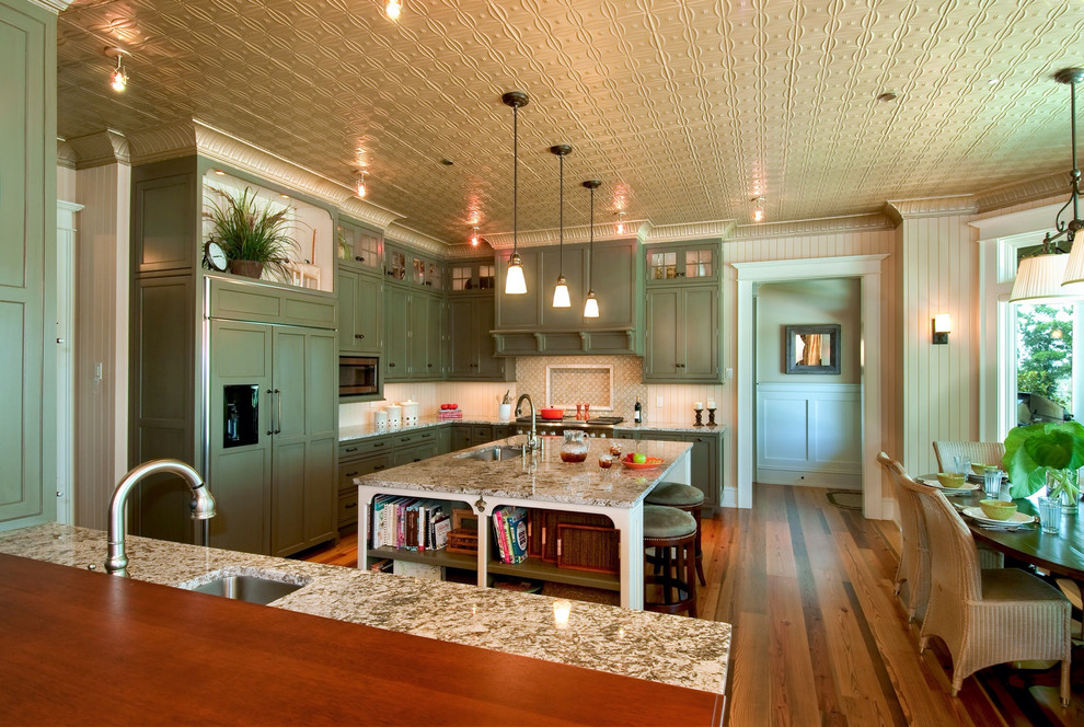 Klassische Wohnküche in L-Form mit Schrankfronten mit vertiefter Füllung, grünen Schränken, Elektrogeräten mit Frontblende, Waschbecken, Granit-Arbeitsplatte und Mauersteinen in Charleston