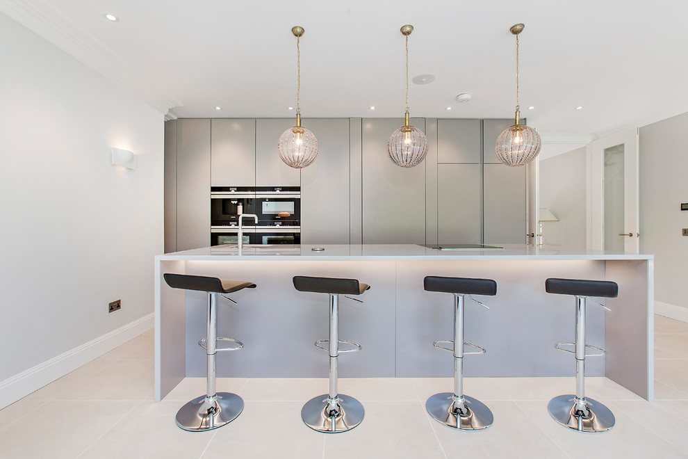 Zweizeilige Moderne Küche mit flächenbündigen Schrankfronten, grauen Schränken, schwarzen Elektrogeräten, Kücheninsel und grauem Boden in London