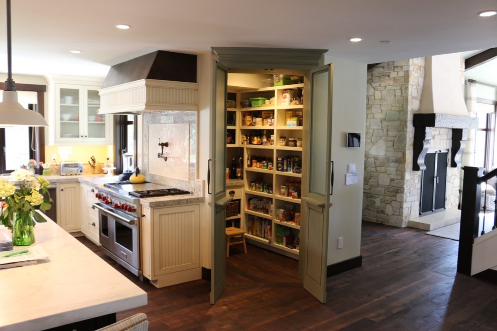 Lantlig inredning av ett mellanstort kök och matrum, med luckor med infälld panel, vita skåp, granitbänkskiva, grått stänkskydd, stänkskydd i sten, rostfria vitvaror, mörkt trägolv och en köksö