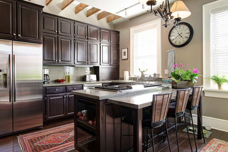 Exempel på ett klassiskt kök, med luckor med upphöjd panel, skåp i mörkt trä, bänkskiva i betong, rostfria vitvaror, mellanmörkt trägolv och en köksö