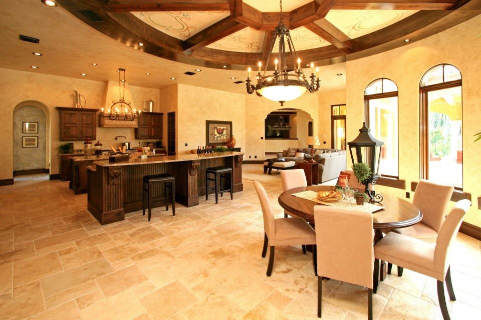 Example of a large tuscan l-shaped travertine floor and beige floor kitchen design in Orlando with an undermount sink, raised-panel cabinets, dark wood cabinets, quartzite countertops, beige backsplash, paneled appliances and two islands