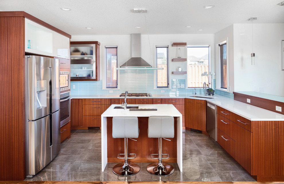 Kitchen - modern u-shaped kitchen idea in Charleston with an undermount sink, flat-panel cabinets, medium tone wood cabinets, blue backsplash, glass tile backsplash, stainless steel appliances and an island