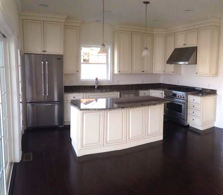 Example of a mid-sized transitional l-shaped dark wood floor eat-in kitchen design in New York with white cabinets, black backsplash, stainless steel appliances, an island, an undermount sink and raised-panel cabinets
