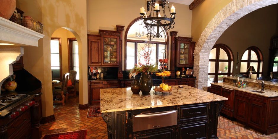 Example of a mid-sized brick floor enclosed kitchen design in Orlando with an undermount sink, beaded inset cabinets, beige cabinets, granite countertops, black backsplash, stone slab backsplash, stainless steel appliances and two islands