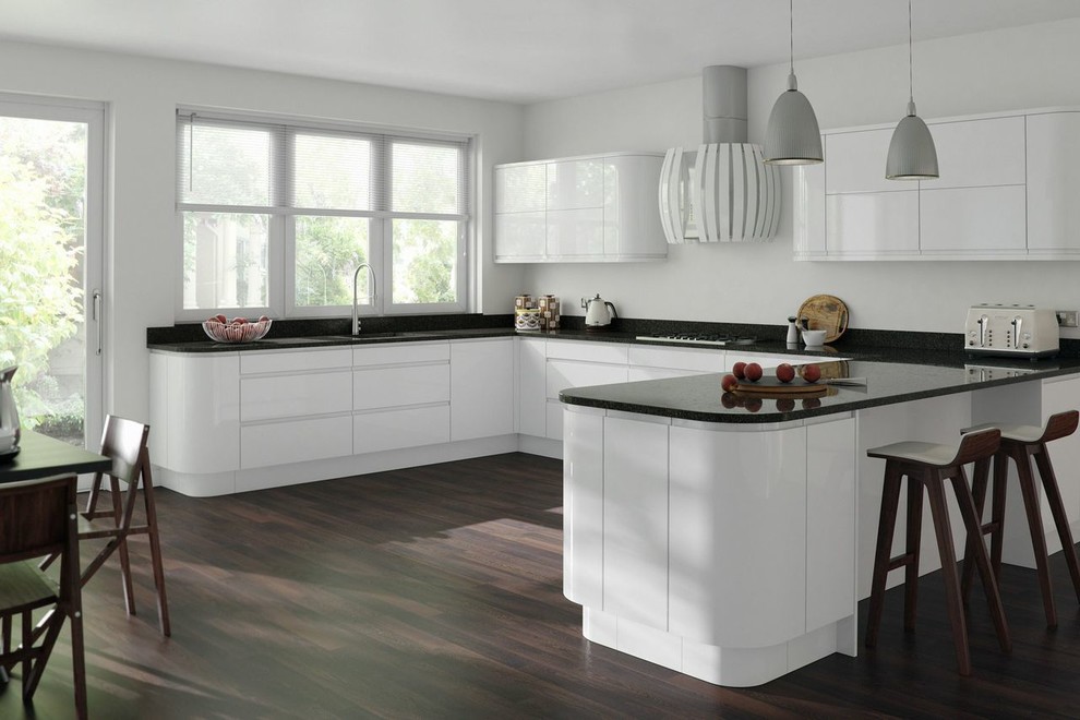 Modern inredning av ett stort kök, med en undermonterad diskho, släta luckor, vita skåp, bänkskiva i onyx, svart stänkskydd, mörkt trägolv och en halv köksö