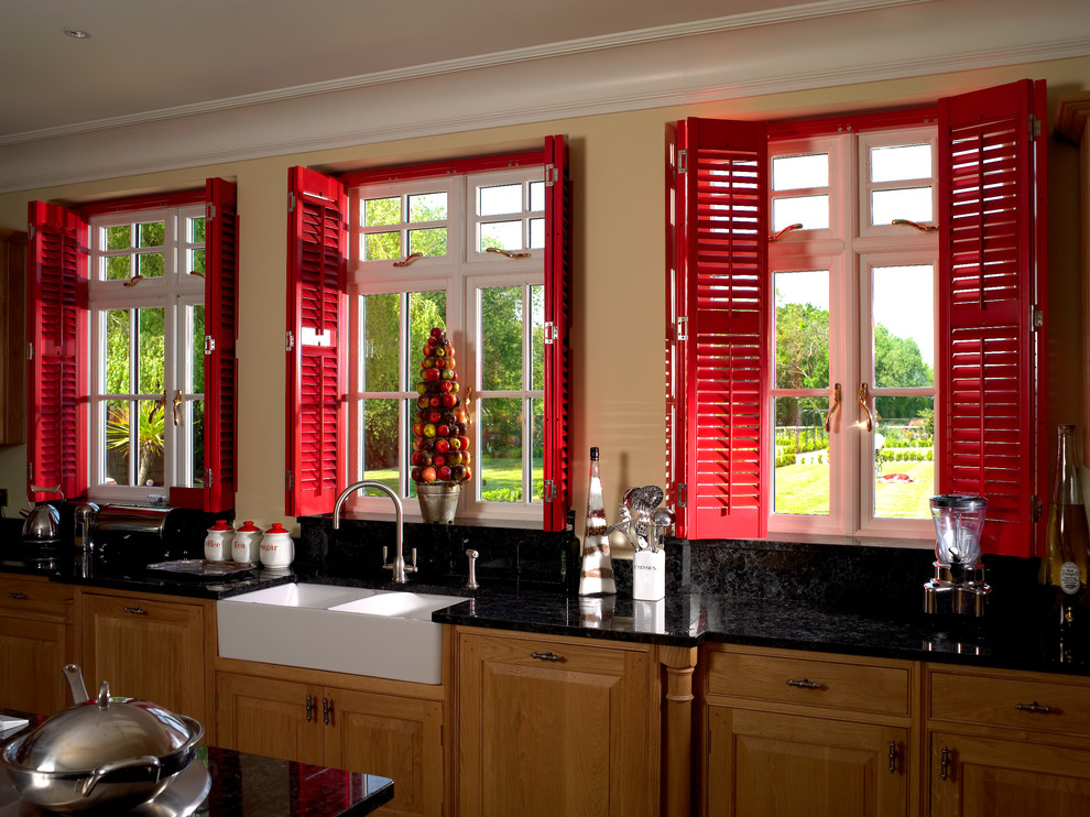 This is an example of a farmhouse kitchen/diner in London with a belfast sink, medium wood cabinets and recessed-panel cabinets.