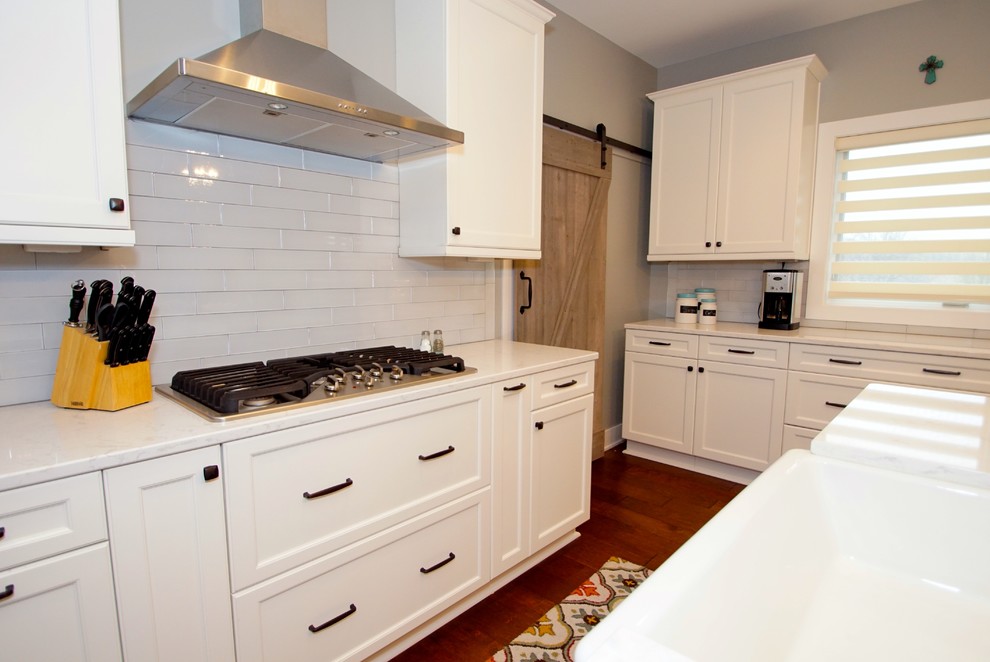 Klassisk inredning av ett stort kök och matrum, med en rustik diskho, skåp i shakerstil, vita skåp, bänkskiva i kvarts, vitt stänkskydd, stänkskydd i glaskakel, rostfria vitvaror, mellanmörkt trägolv och en köksö
