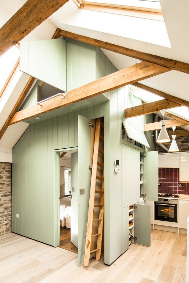 Modelo de cocina de estilo de casa de campo pequeña con armarios con paneles lisos, puertas de armario verdes, suelo de madera clara, salpicadero rojo y salpicadero de azulejos de cerámica