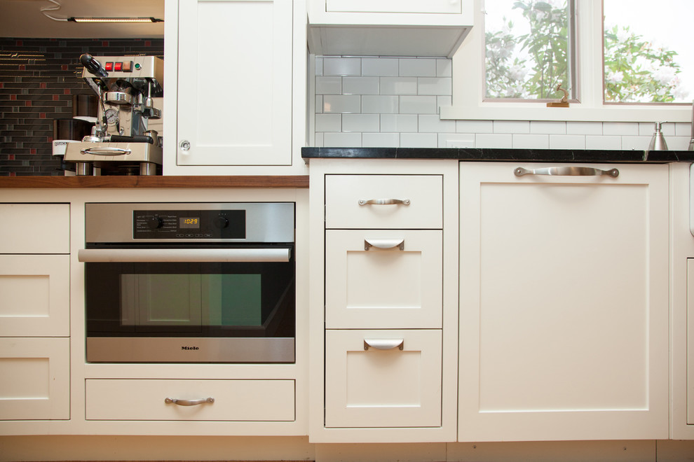 This is an example of a medium sized classic galley kitchen/diner in Portland with a belfast sink, shaker cabinets, white cabinets, soapstone worktops, yellow splashback, ceramic splashback, stainless steel appliances, cork flooring and no island.