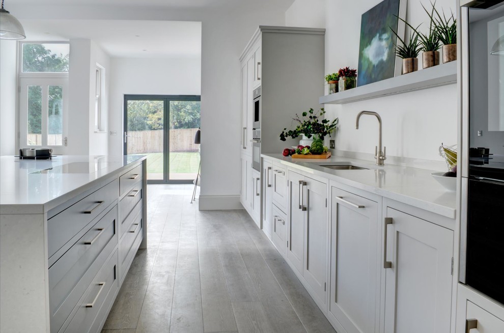 Inspiration för ett stort funkis vit linjärt vitt kök med öppen planlösning, med luckor med infälld panel, grå skåp, bänkskiva i kvartsit, rostfria vitvaror, mellanmörkt trägolv, en köksö och beiget golv