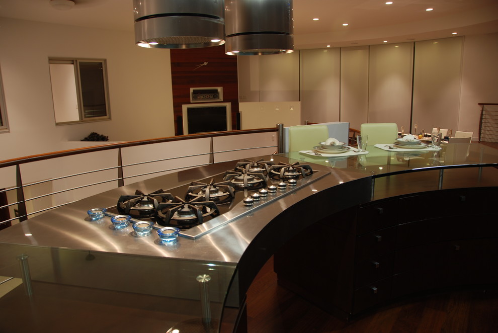 Foto di una cucina moderna di medie dimensioni con ante lisce, ante in legno bruno, top in vetro, paraspruzzi con piastrelle di vetro, elettrodomestici in acciaio inossidabile e pavimento in legno massello medio