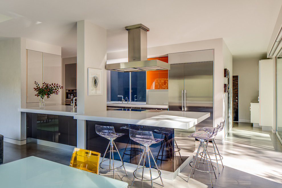 Immagine di una grande cucina moderna con elettrodomestici in acciaio inossidabile, lavello sottopiano, ante lisce, ante grigie, top in superficie solida, paraspruzzi blu, paraspruzzi con lastra di vetro e penisola