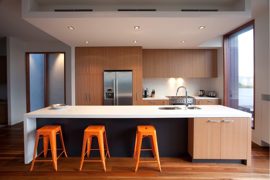 Immagine di una cucina design con lavello a doppia vasca, ante in legno chiaro, paraspruzzi bianco e pavimento in legno massello medio