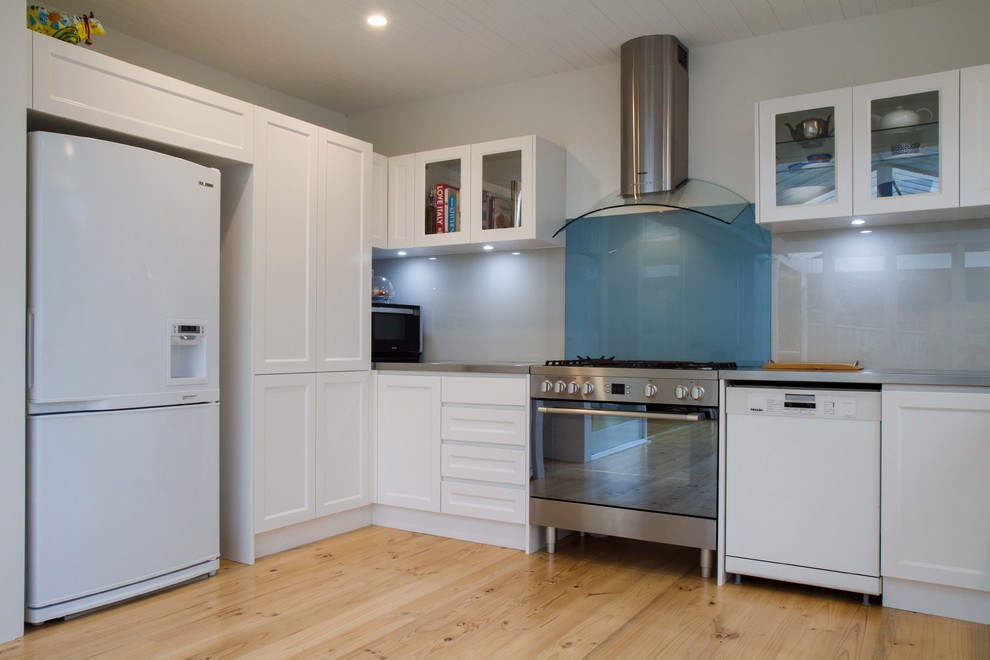 メルボルンにある中くらいなトラディショナルスタイルのおしゃれなキッチン (シェーカースタイル扉のキャビネット、ステンレスカウンター、青いキッチンパネル、ガラス板のキッチンパネル、淡色無垢フローリング、アイランドなし) の写真