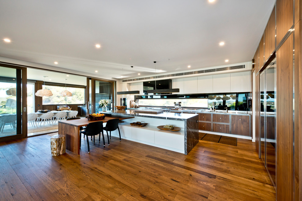 Example of a trendy l-shaped medium tone wood floor and brown floor open concept kitchen design in Melbourne with flat-panel cabinets, medium tone wood cabinets, wood countertops, window backsplash and an island