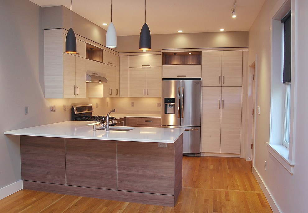 This is an example of a medium sized contemporary u-shaped kitchen in Boston with a submerged sink, flat-panel cabinets, light wood cabinets, engineered stone countertops, stainless steel appliances, light hardwood flooring and a breakfast bar.