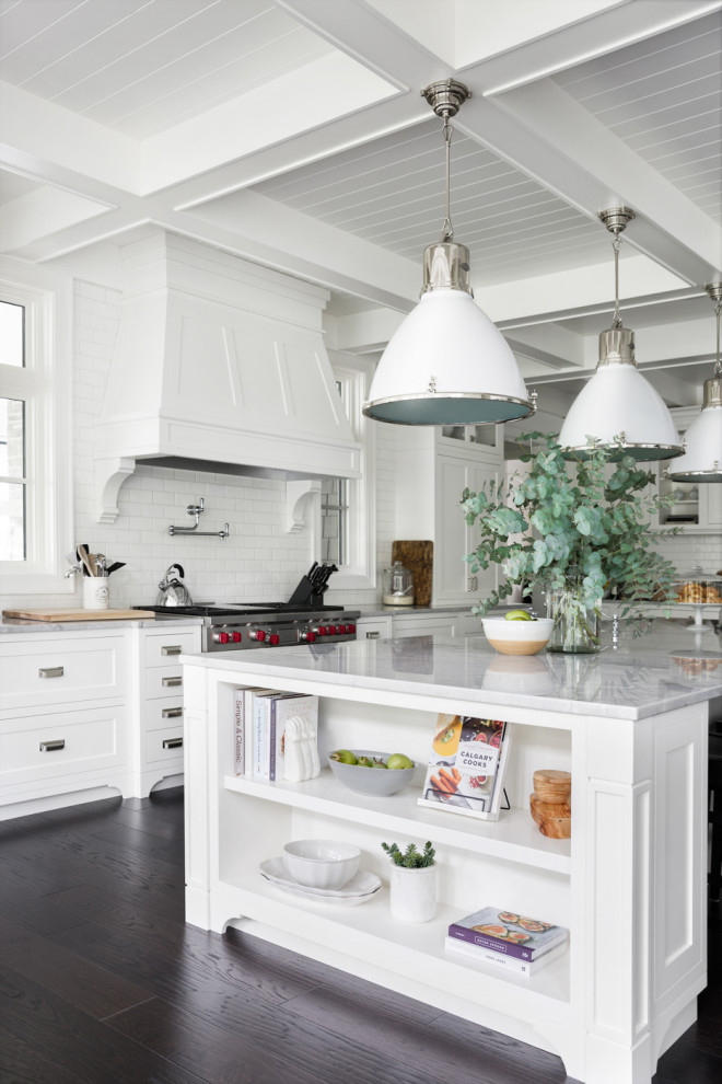 Idées déco pour une cuisine classique avec un placard à porte shaker, des portes de placard blanches, une crédence blanche, une crédence en carrelage métro, un électroménager en acier inoxydable, parquet foncé, îlot, un sol marron, un plan de travail blanc et un plafond à caissons.