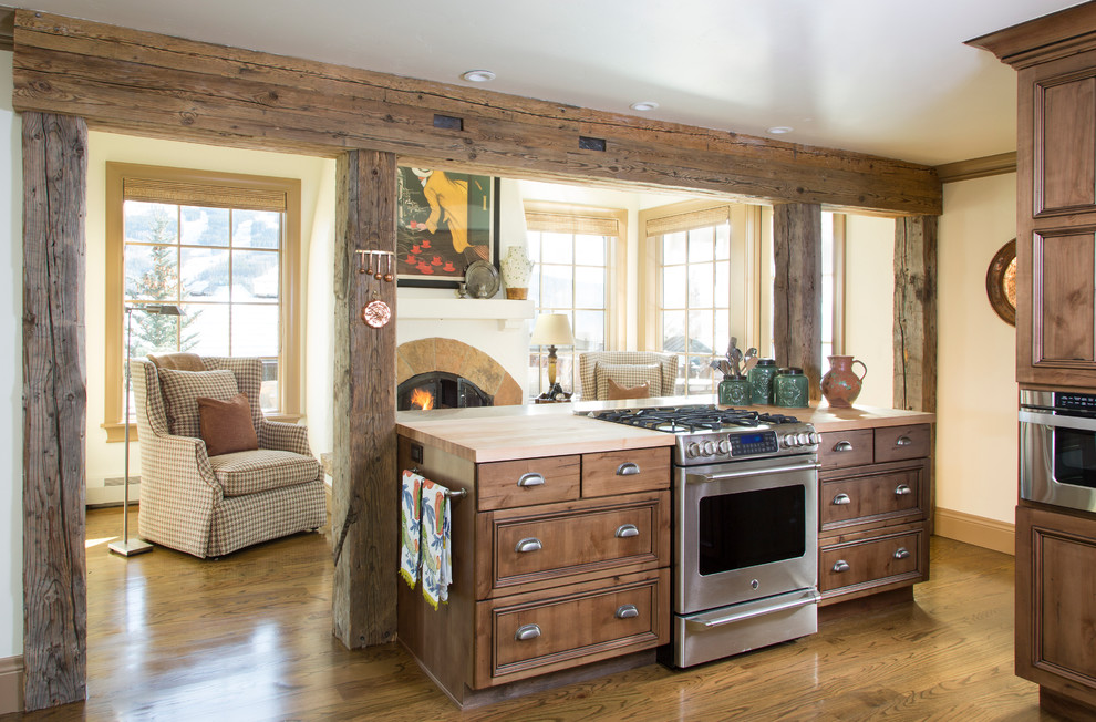 Inspiration for a rustic medium tone wood floor kitchen remodel in Denver with recessed-panel cabinets, medium tone wood cabinets, wood countertops, stainless steel appliances and an island