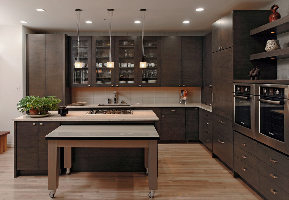 Example of a mid-sized trendy l-shaped light wood floor and beige floor eat-in kitchen design in DC Metro with an undermount sink, flat-panel cabinets, dark wood cabinets, glass tile backsplash, an island, granite countertops, beige backsplash and stainless steel appliances