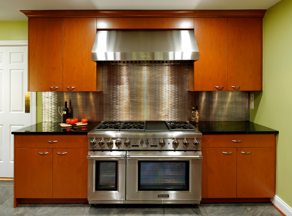 ワシントンD.C.にある高級な中くらいなエクレクティックスタイルのおしゃれなキッチン (フラットパネル扉のキャビネット、中間色木目調キャビネット、御影石カウンター、メタリックのキッチンパネル、メタルタイルのキッチンパネル、シルバーの調理設備、アイランドなし、アンダーカウンターシンク、セラミックタイルの床) の写真