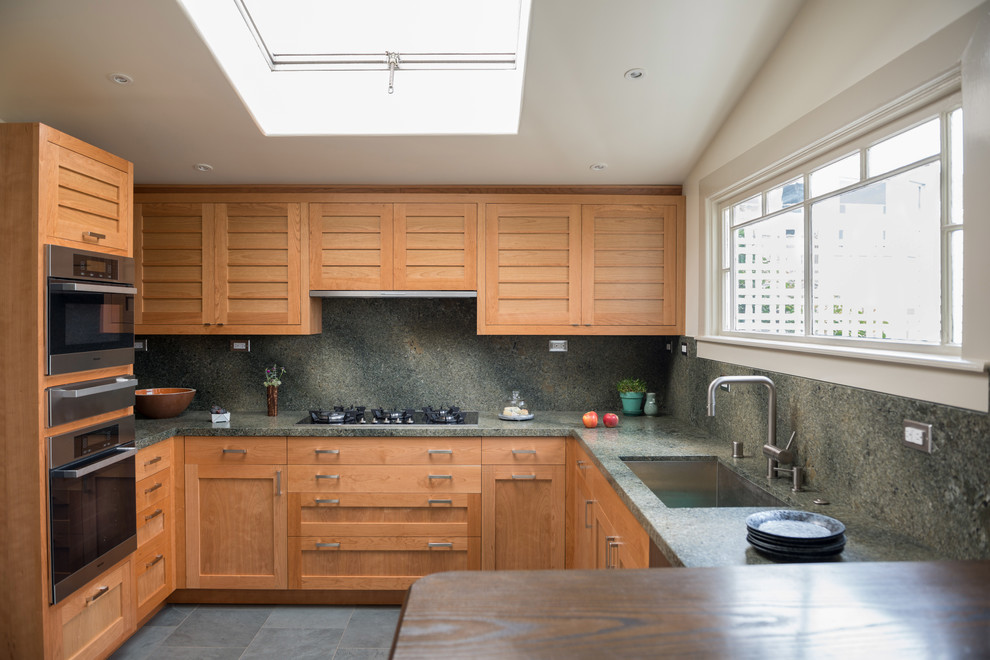 Idée de décoration pour une cuisine design en bois brun avec un évier encastré, un placard à porte shaker, une crédence grise et un électroménager en acier inoxydable.