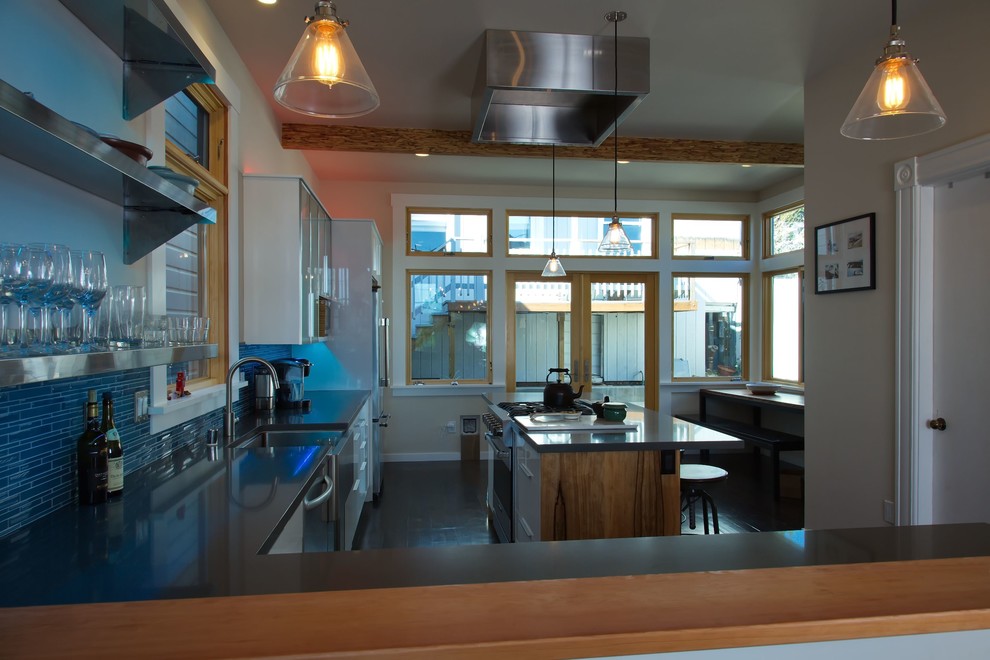 サンフランシスコにある中くらいなコンテンポラリースタイルのおしゃれなキッチン (エプロンフロントシンク、フラットパネル扉のキャビネット、白いキャビネット、クオーツストーンカウンター、青いキッチンパネル、ガラスタイルのキッチンパネル、シルバーの調理設備、クッションフロア、茶色い床、グレーのキッチンカウンター) の写真